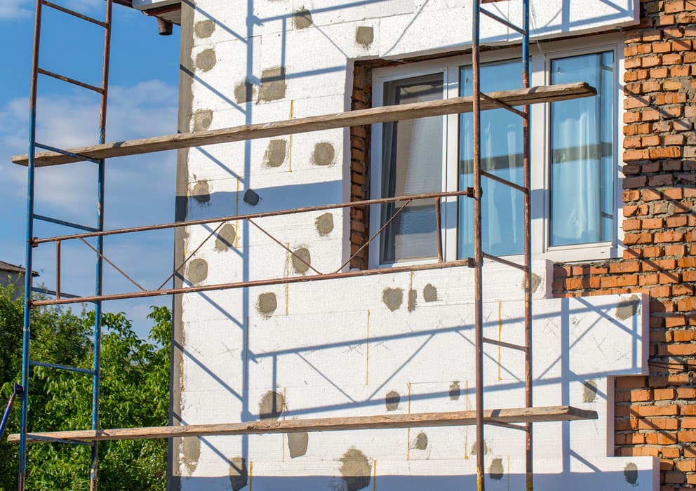 Baugerüst vor einer Hausfassade während der Dämmarbeiten